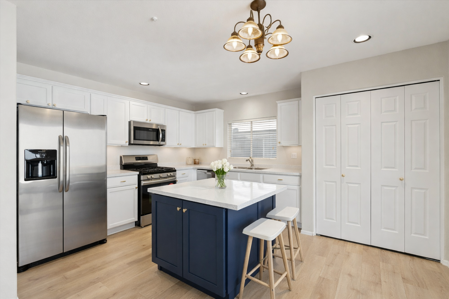 Updated kitchen rendering in North Scottsdale single-family home showcasing white cabinetry, navy kitchen island, quartz countertops, stainless steel appliances, wood flooring, and functional island seating in gated Scottsdale neighborhood