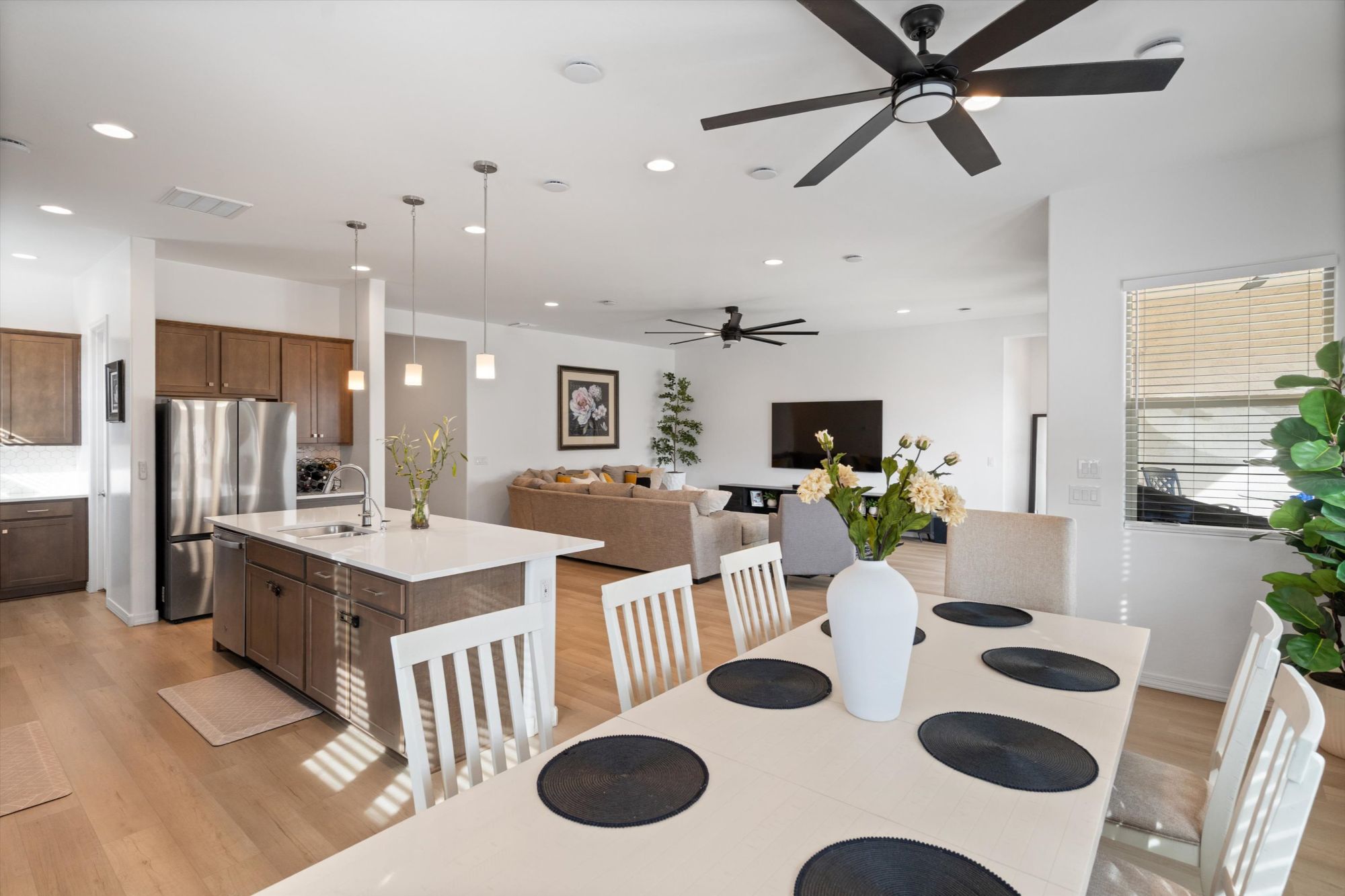 open concept kitchen and living room in Alamar Avondale AZ home with quartz countertops, large island, luxury vinyl plank flooring and modern layout better than new construction