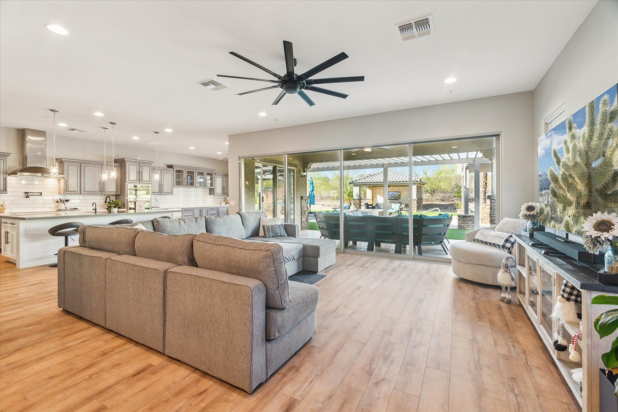 Open-concept luxury home interior in North Peoria AZ featuring sliding glass wall and seamless indoor-outdoor living overlooking a resort-style backyard