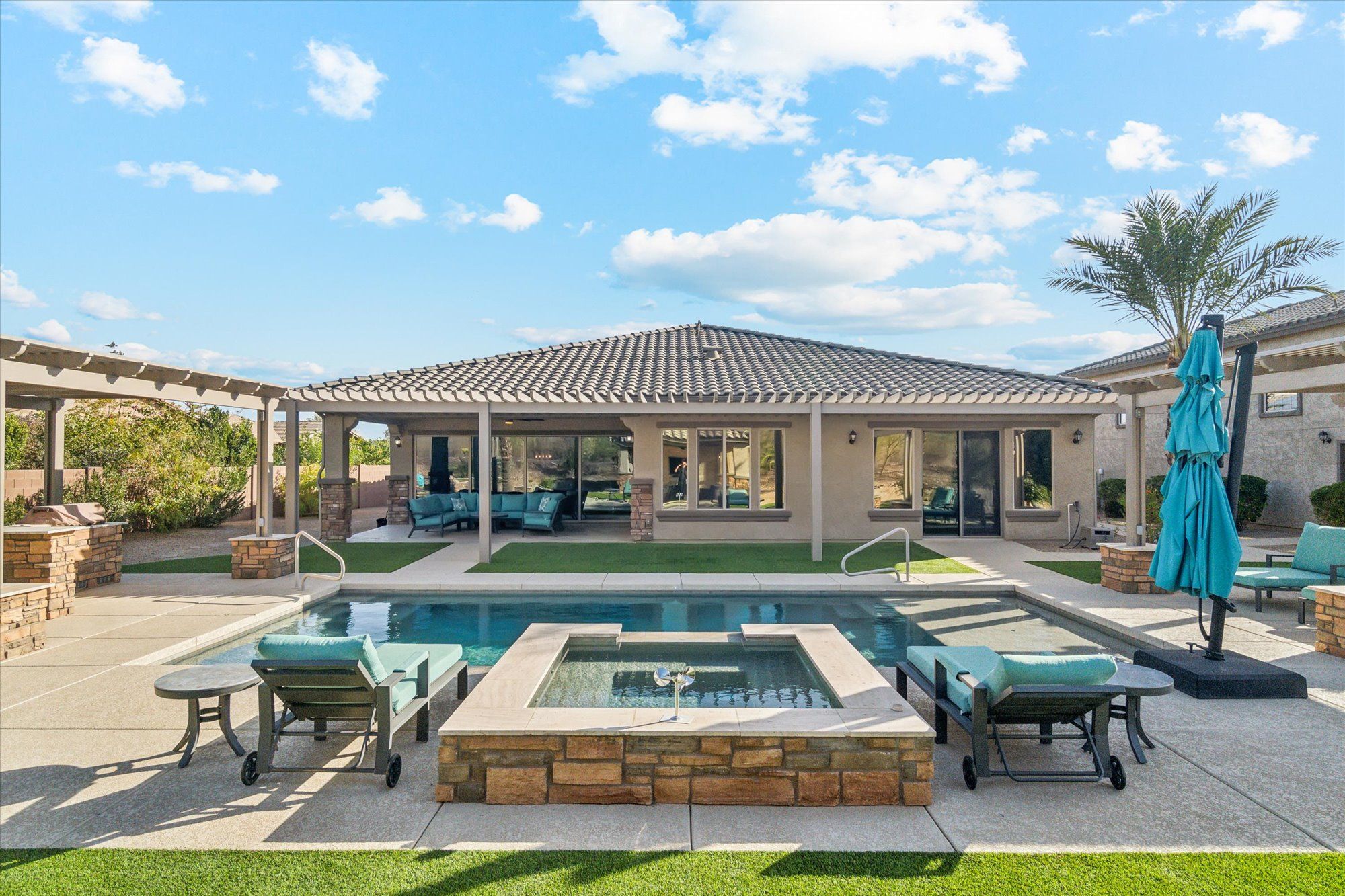 Resort-style backyard of a North Peoria AZ luxury home featuring pool, spa, and outdoor entertaining space on a large estate lot