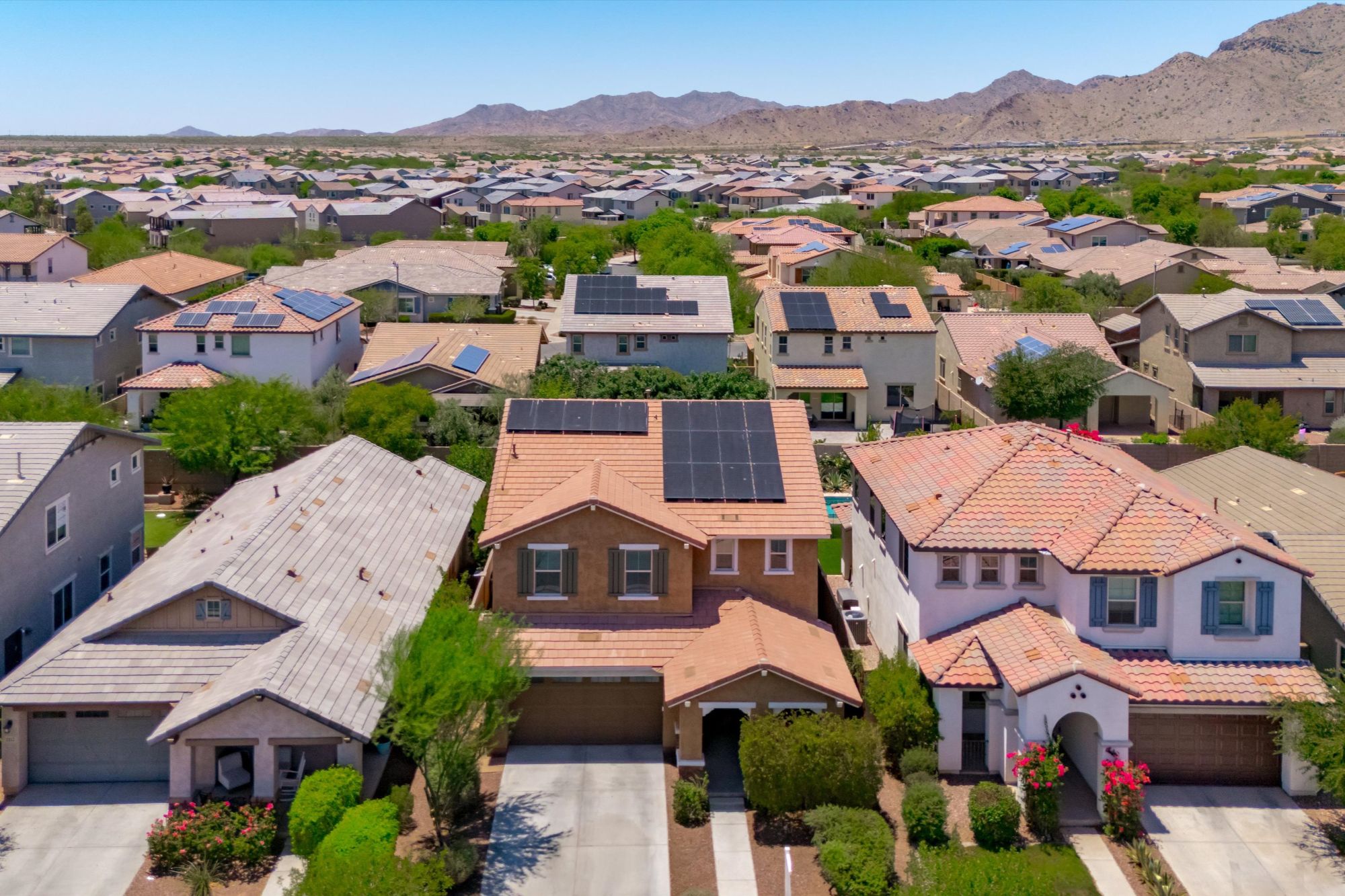 Aerial view of a single-family home in Verrado, Buckeye AZ surrounded by neighboring homes and desert mountain views, illustrating residential properties within the Verrado master-planned community where homes attract strong buyer demand.