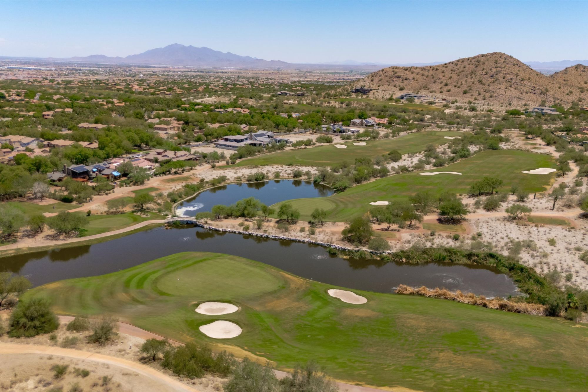 Aerial view of Verrado Golf Club and surrounding neighborhoods in Verrado Buckeye AZ, showcasing desert golf course fairways, mountain views, and the scenic lifestyle that attracts buyers to the Verrado real estate market.