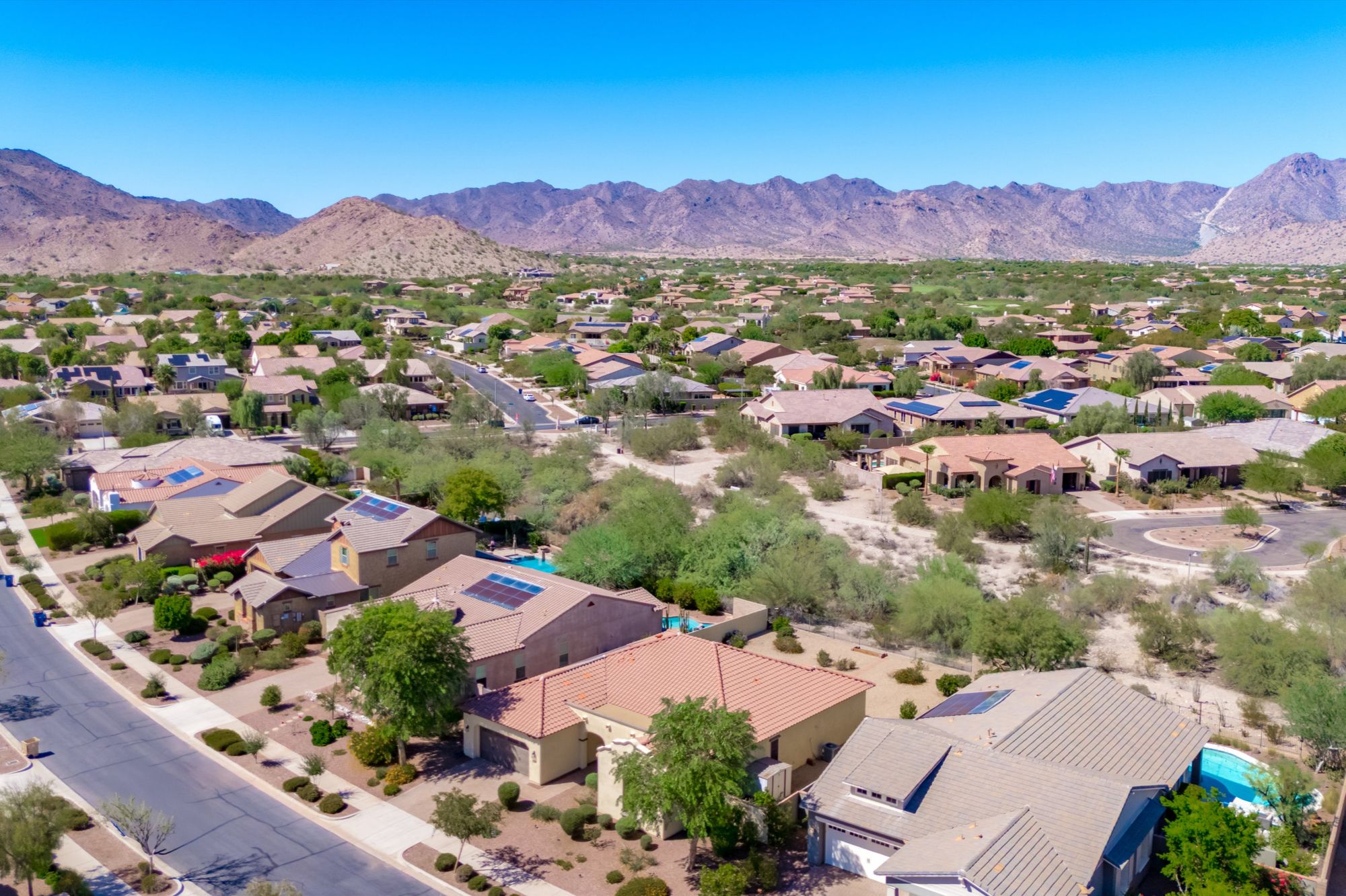Aerial view of Verrado, a master-planned community in Buckeye AZ near Luke Air Force Base, showing tree-lined streets and mountain backdrop