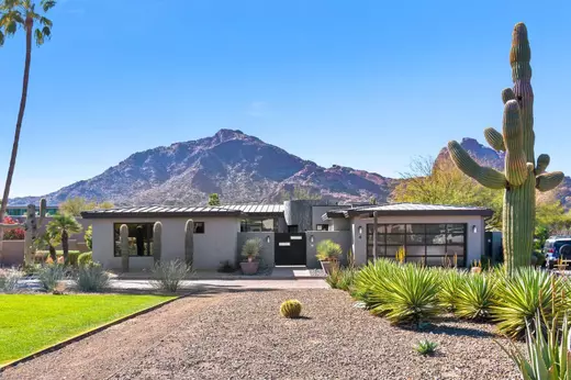 Modern Arizona home with desert landscaping and panoramic Camelback Mountain views under a clear blue sky, showcasing the natural beauty and lifestyle appeal drawing people to move to Arizona.