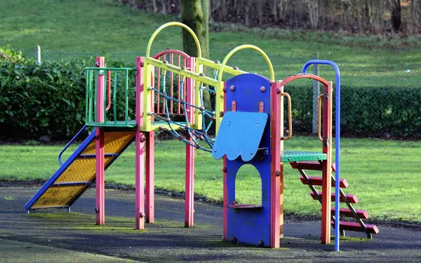 Playground equipment in an open Portland-area park surrounded by grass and trees