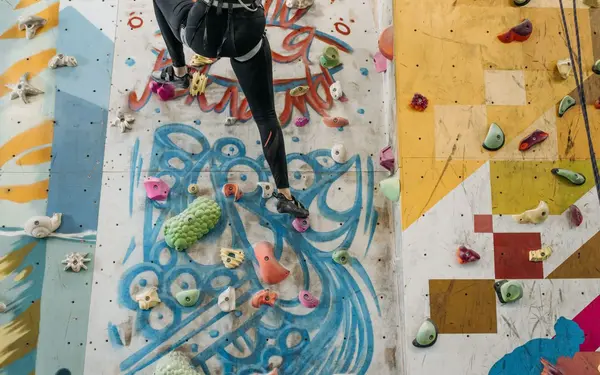 Climber scaling a colorful indoor rock climbing wall