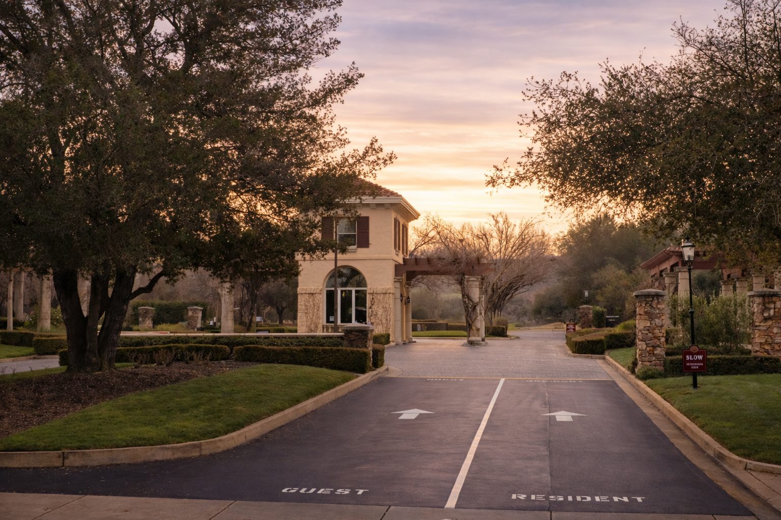 Gated entrance to Ruby Hill neighborhood in Pleasanton, California at dusk with warm lighting and tree-lined drive