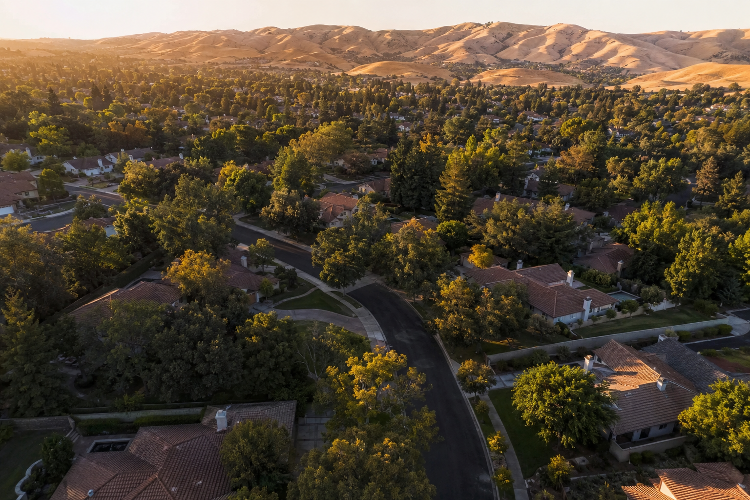 Aerial view of Pleasanton California residential neighborhood with rolling hills in morning light