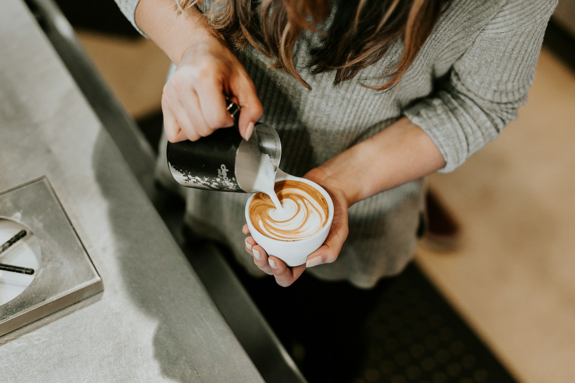 Person making latte art holding a coffee