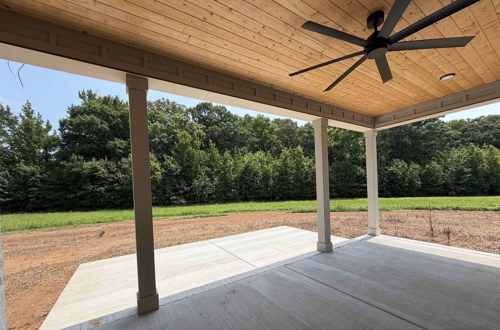 Covered back porch with a ceiling fan overlooking a wooded acreage lot in Sydney School Estates, Hazel Green, Alabama