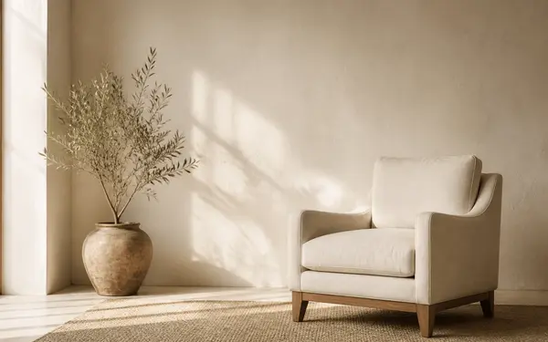Serene single-level home interior with a linen chair, plaster wall, and a plant in afternoon light