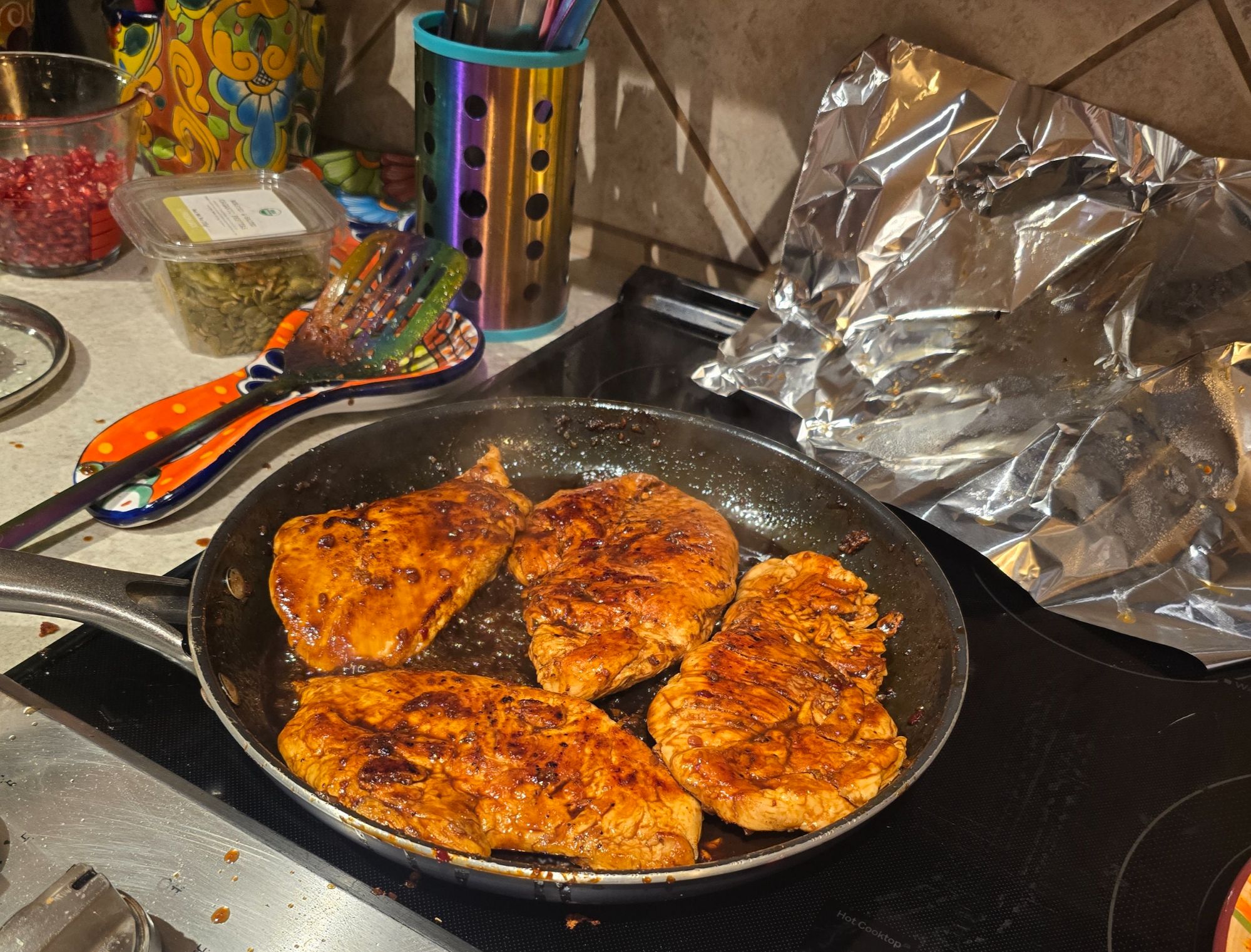 Four chicken breasts searing in a skillet, browned and glossy