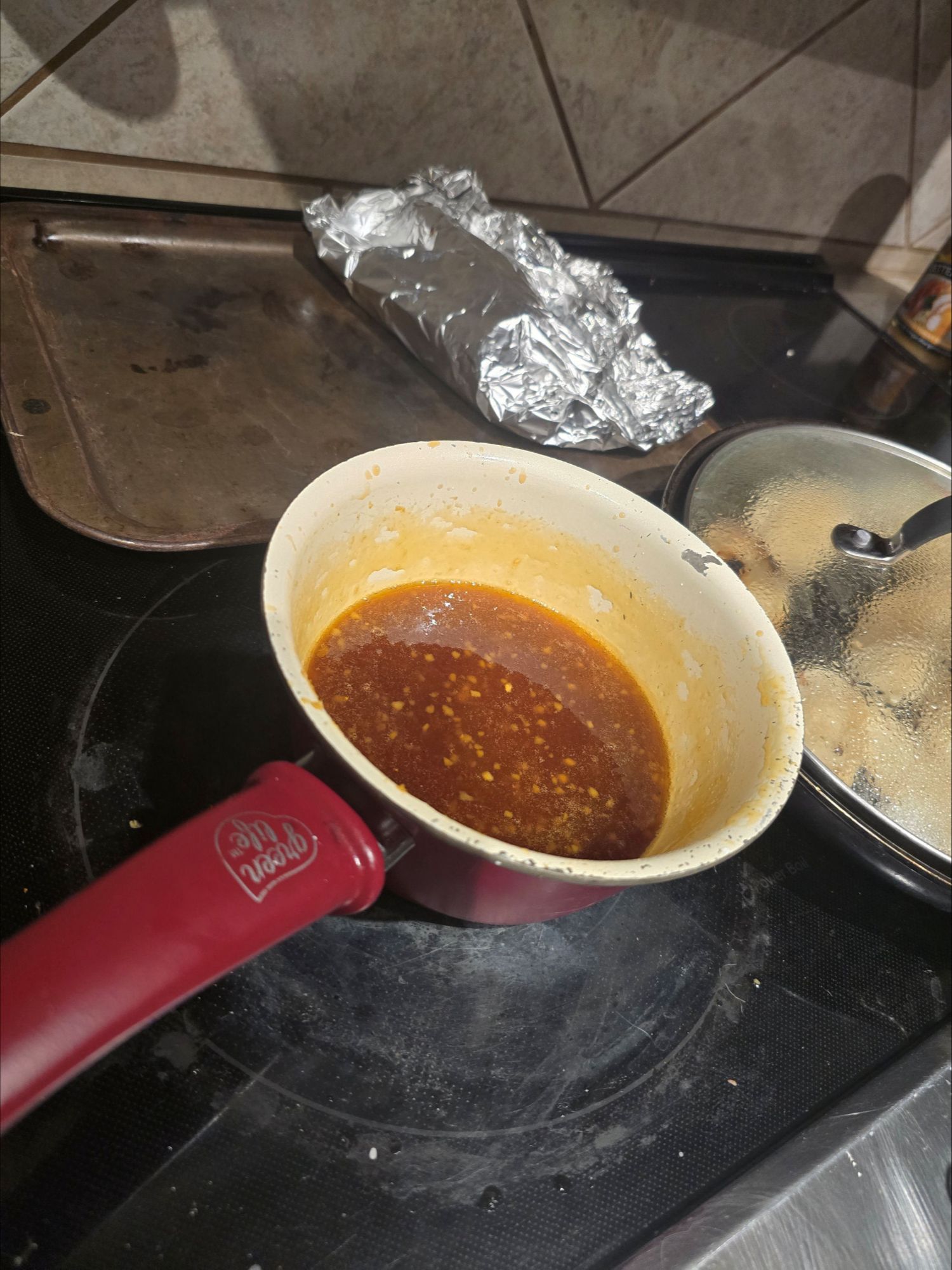 Small saucepan of homemade lemon sauce simmering on the stovetop, showing a glossy citrus glaze with visible garlic and zest for Chinese-style lemon chicken.