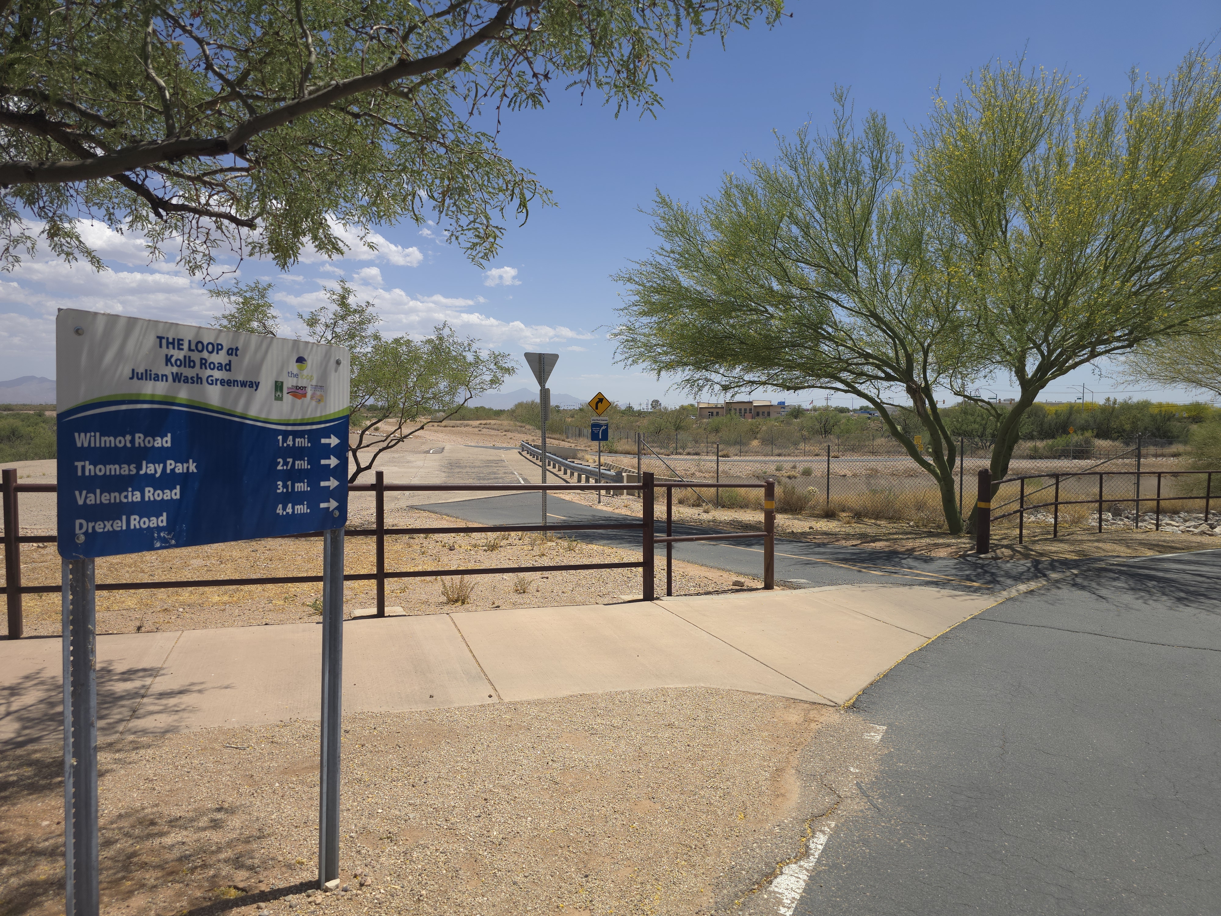 Loop trail entrance at Kolb Road in La Estancia de Tucson with mileage marker sign showing distances to Wilmot, Thomas Jay Park, Valencia, and Drexel Roads