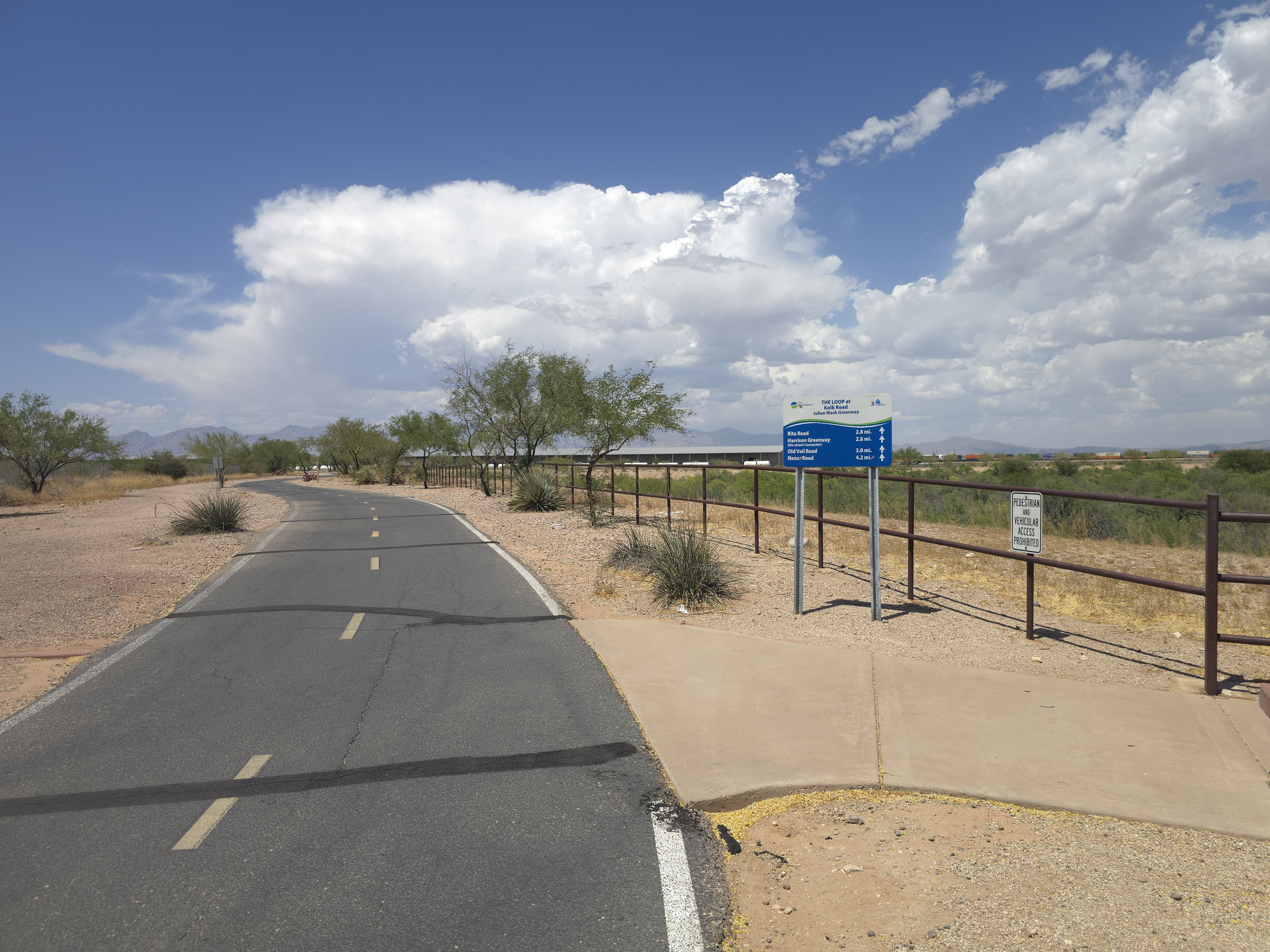 Paved Loop trail at Kolb Road and Julian Wash Greenway with directional signage and desert landscape