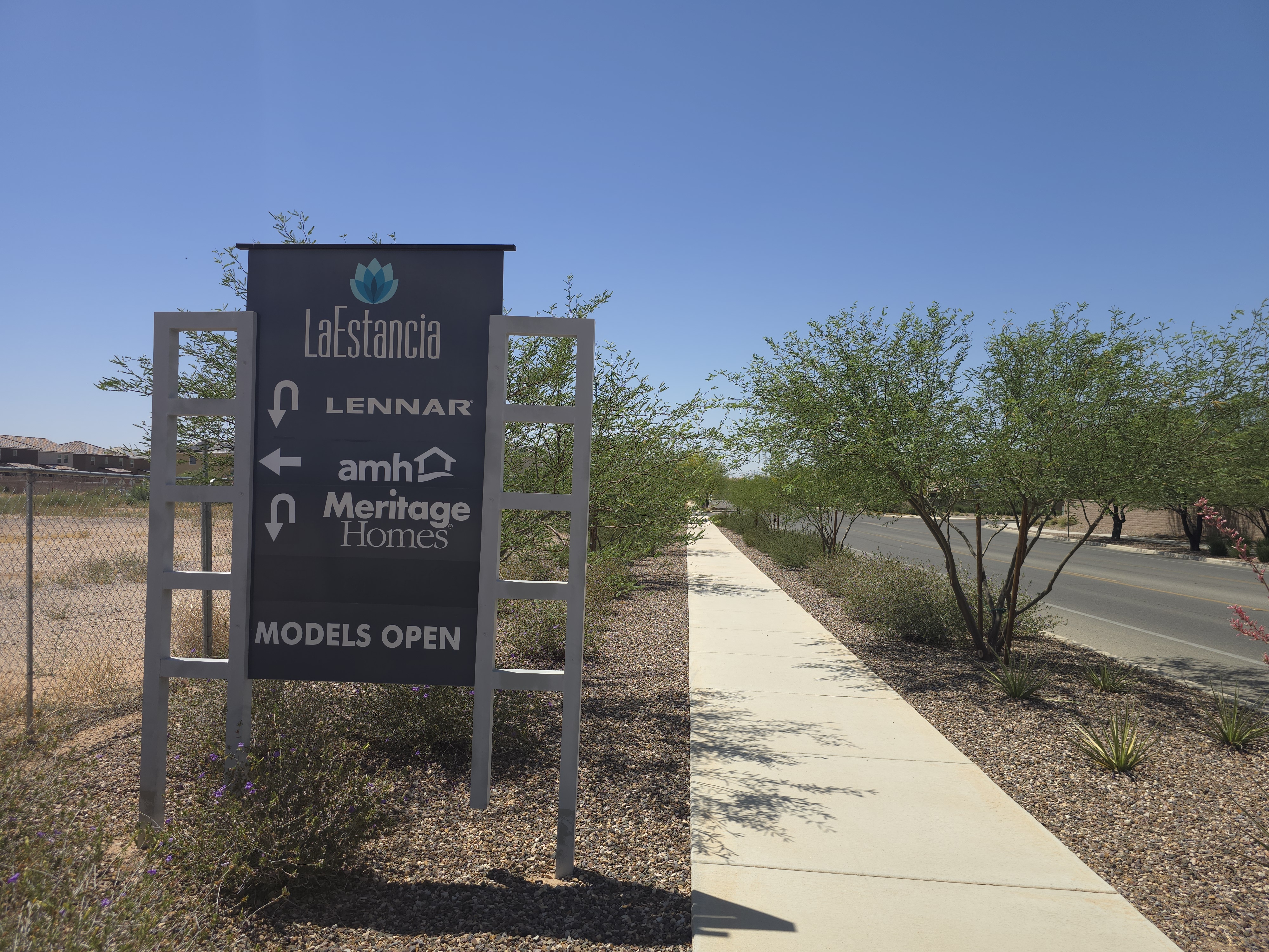 La Estancia community entrance sign listing Lennar, AMH, and Meritage Homes with Models Open directional arrows