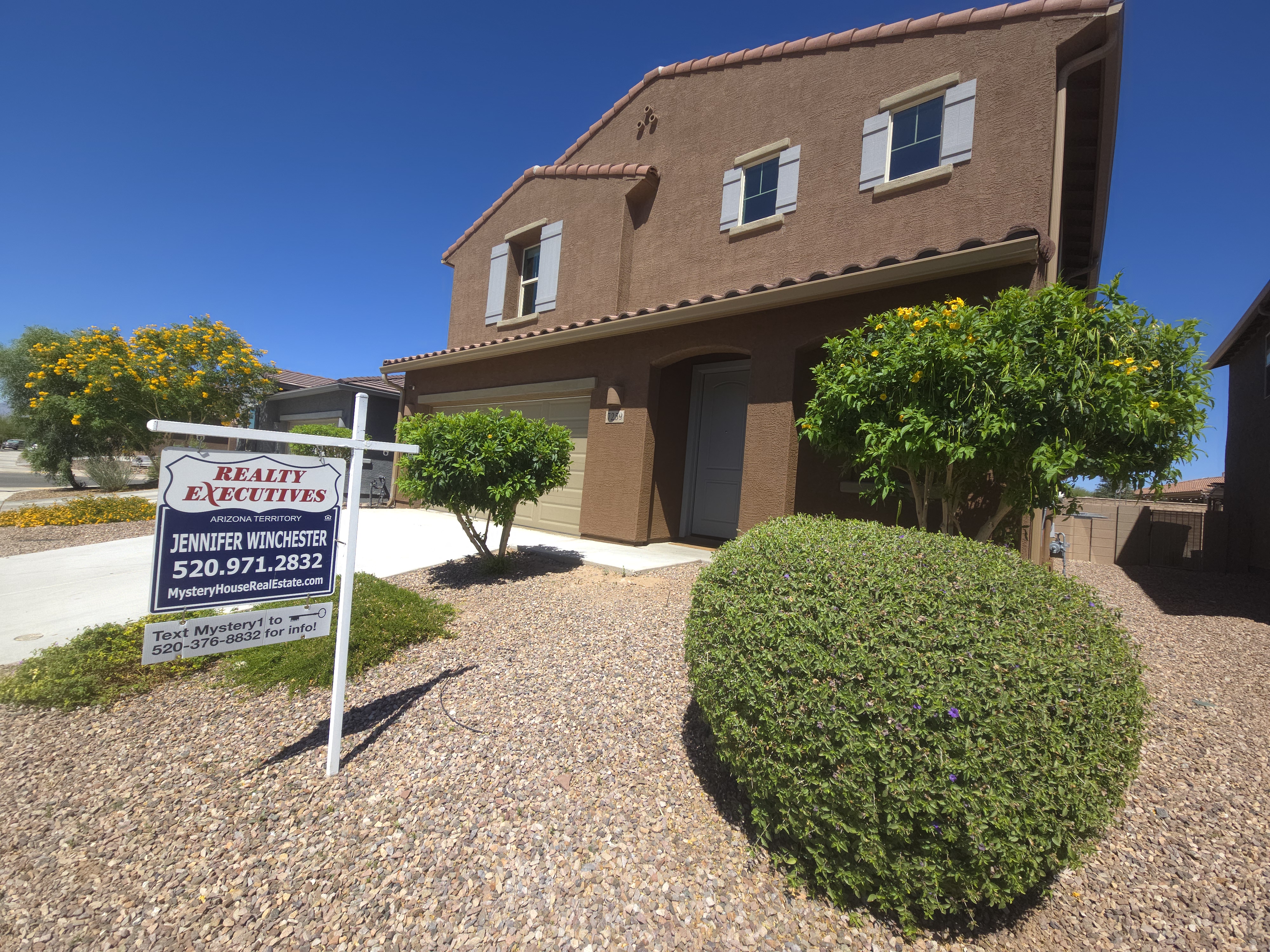 Two-story stucco home at 7259 S Camino Del Cordero in La Estancia de Tucson with a Realty Executives Arizona Territory For Sale sign listing Jennifer Winchester, 520-971-2832, MysteryHouseRealEstate.com