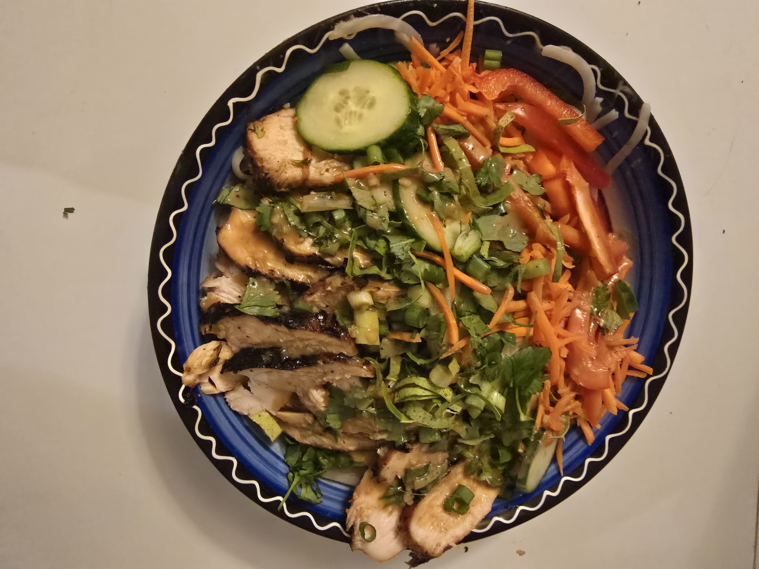 Cold sesame noodle bowl with grilled chicken, fresh herbs, and sliced chilis