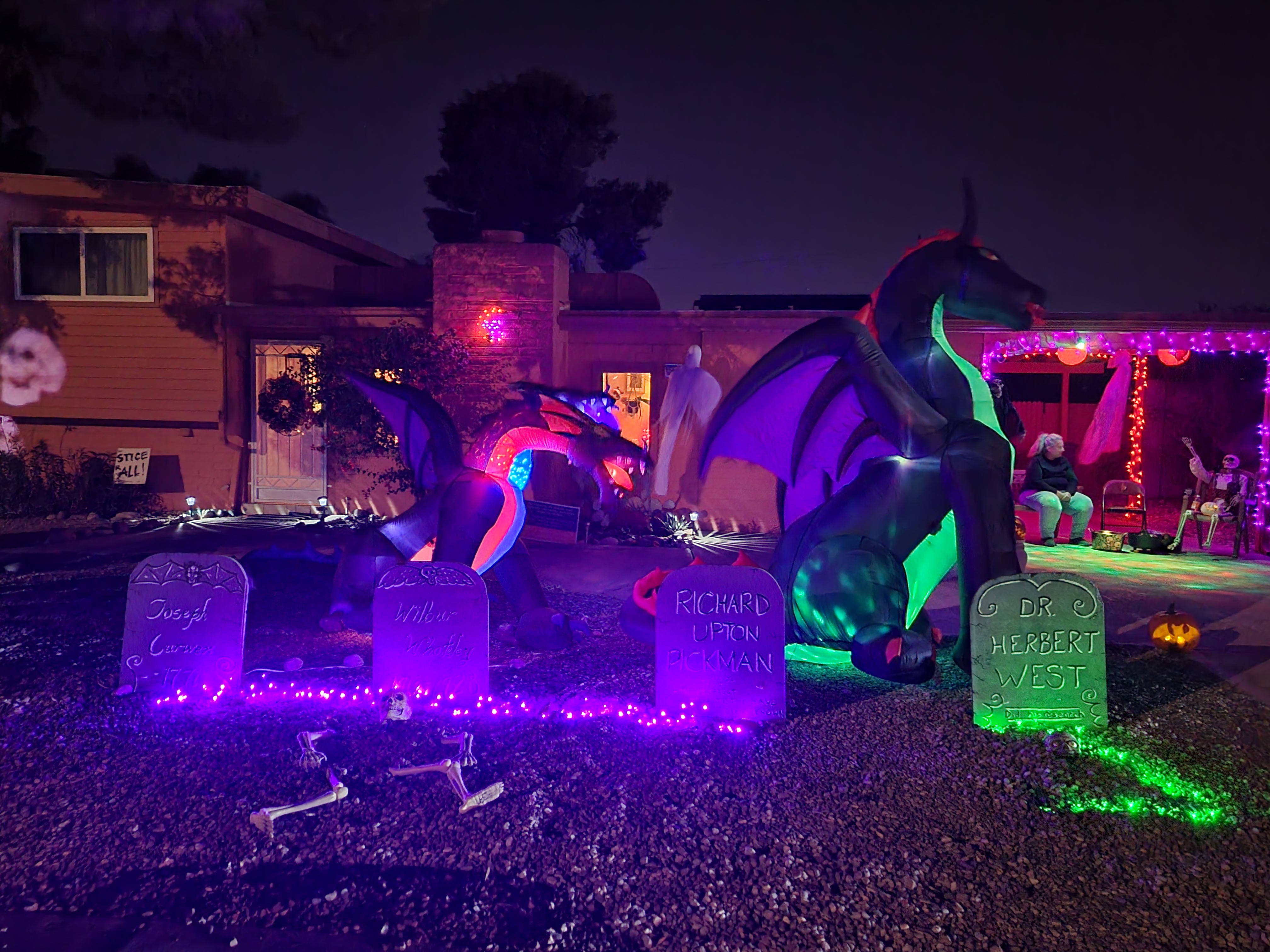 A Tucson home at dusk with the porch light on and Halloween decorations set up along the front walk
