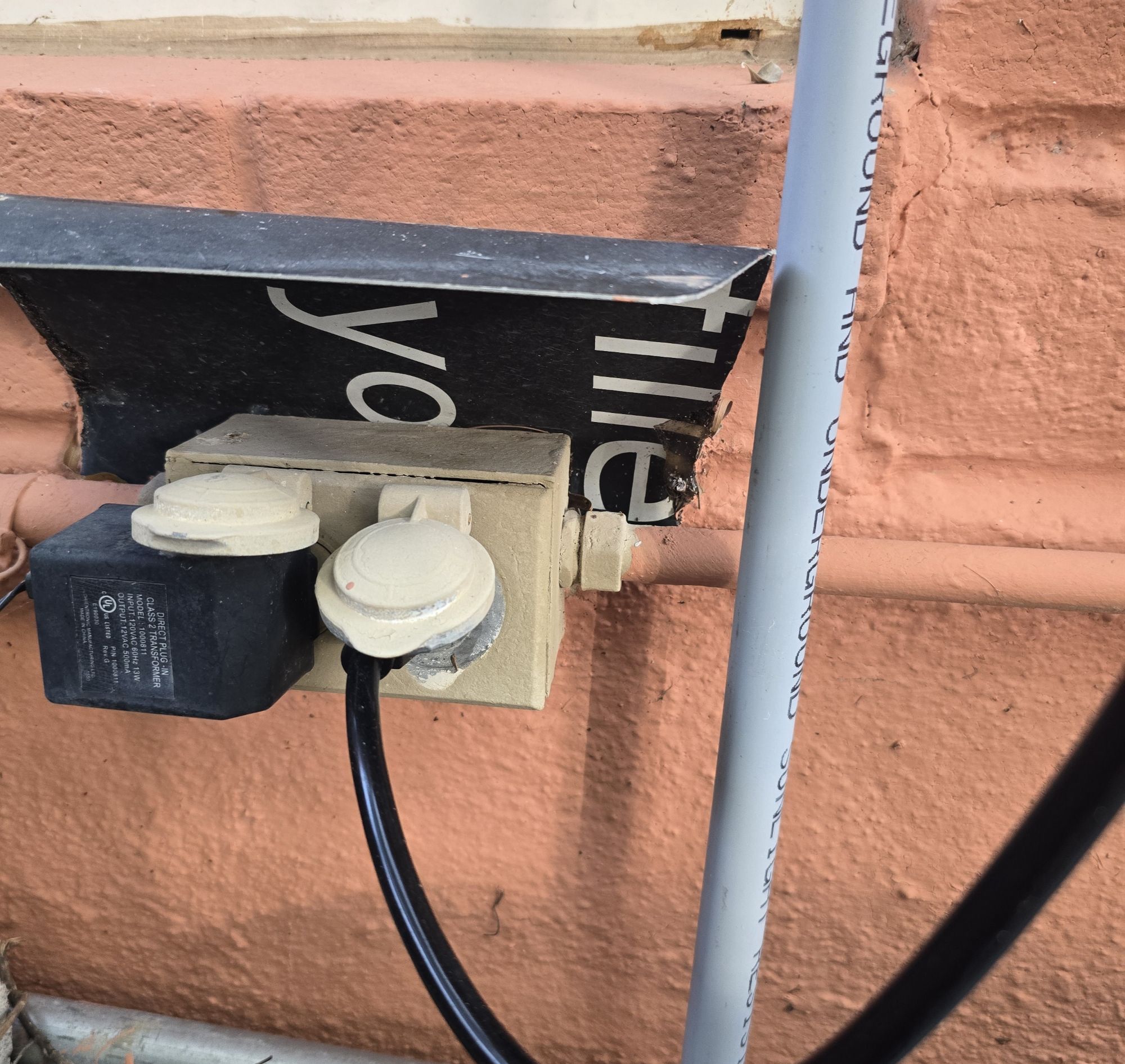An exterior outlet on a home's front wall with an extension cord plugged in
