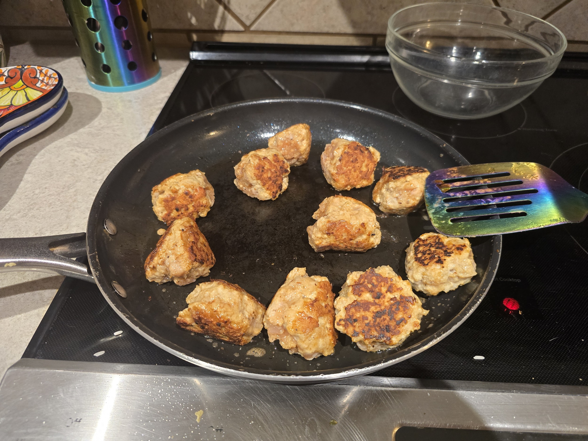 Meatballs searing in a hot skillet