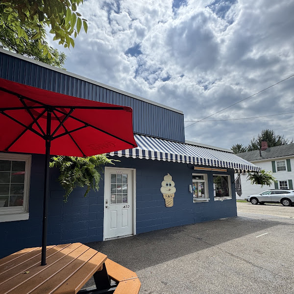 A nostalgic red-and-white American drive-in ice cream stand with a striped awning and a waffle-cone soft serve in the foreground in Springboro Ohio