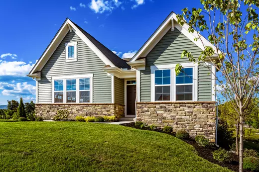 Charming single-story brick home in a 55+ community with manicured lawn and inviting front porch