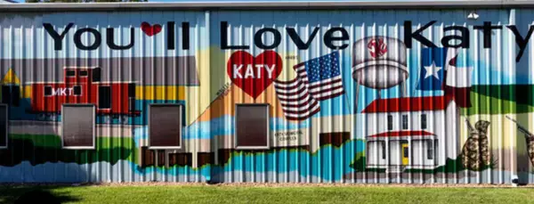 alt = "A truck container painted with "You'll Love Katy" with artwork on the body"