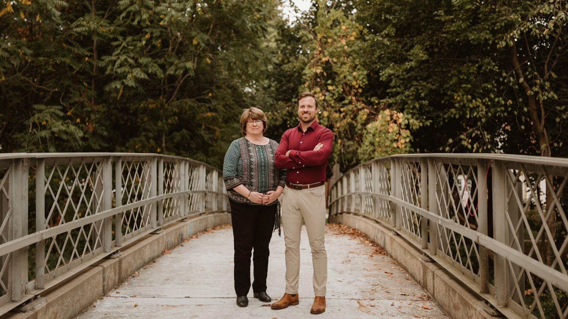 Pat Lotz and Chris of the Pat Lotz Real Estate Group standing on the pedestrian bridge in Downtown Brighton, Michigan