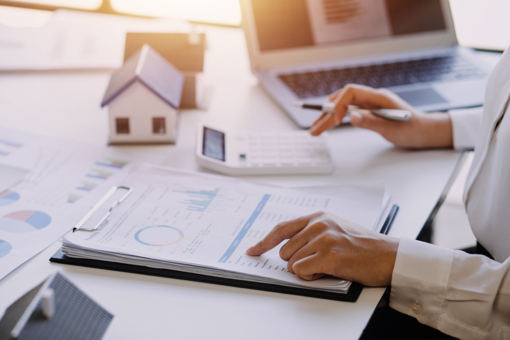Real estate agent reviewing a comparative market analysis report with charts and pricing data to determine a home&rsquo;s listing price