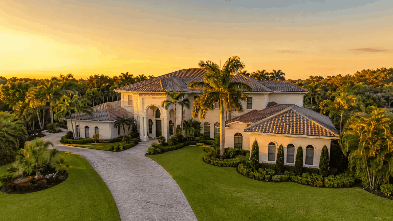 Luxury home exterior in Weston FL photographed at golden hour with tropical landscaping and blue sky