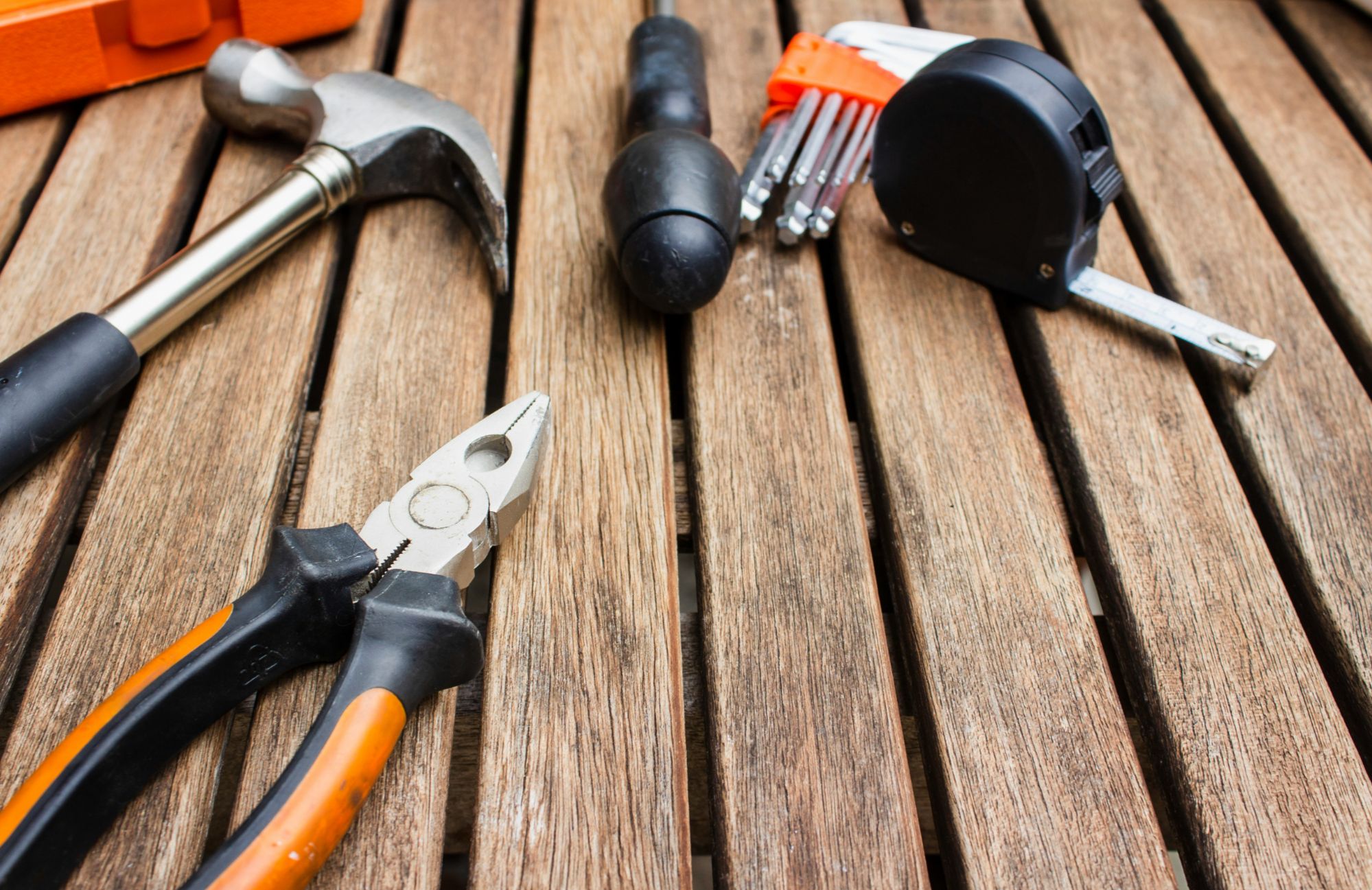 Basic hand tools laid out on a wood deck, ready for prelisting repairs