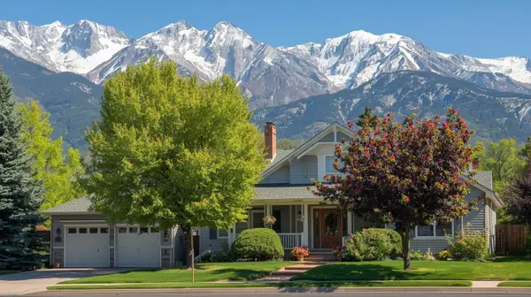 bright spring image of the exterior of a springville utah home with green trees and flowers WITH snowy mountain peaks in the background