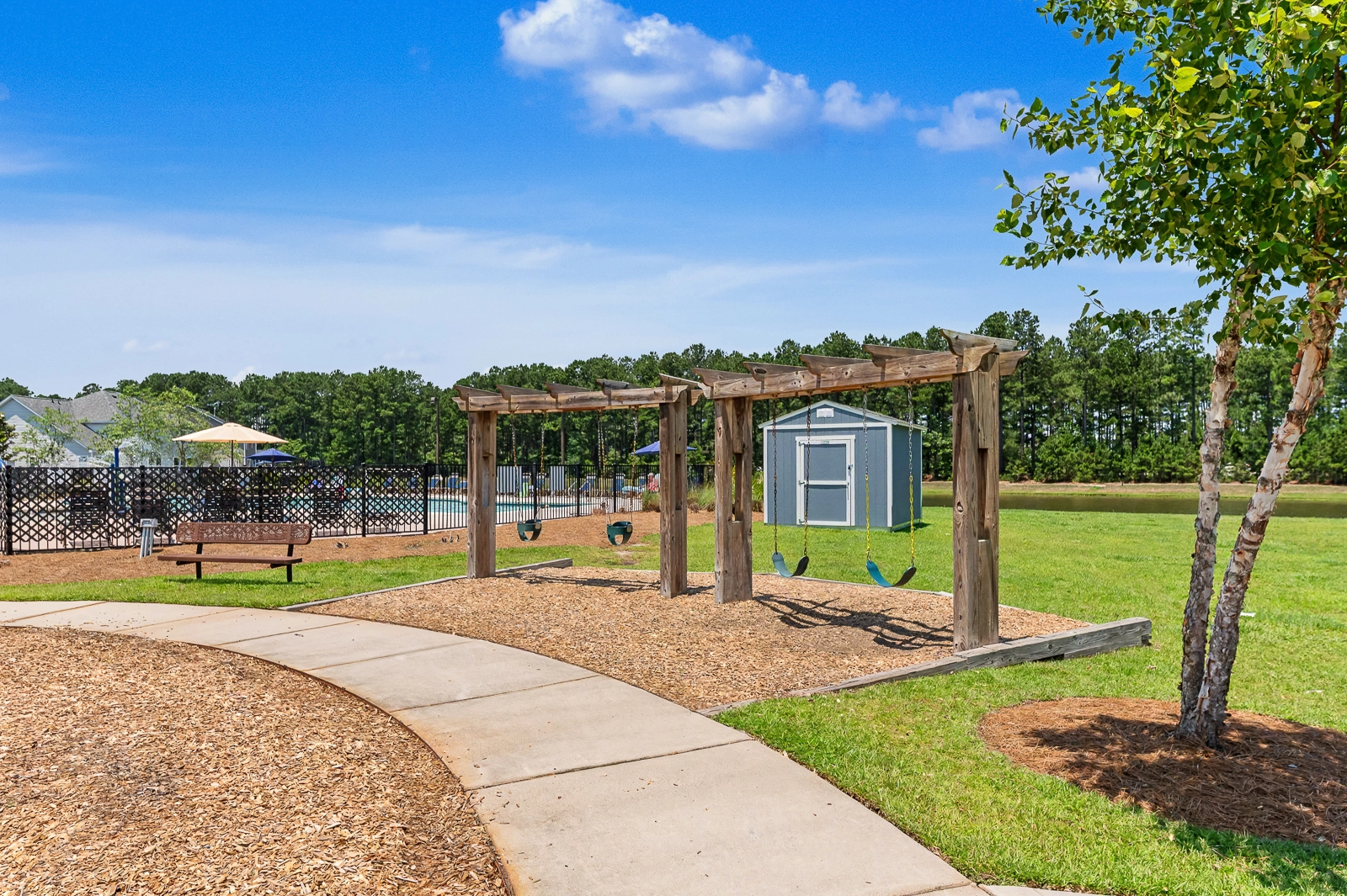 Cane Bay Plantation park in Summerville SC with swing set walking path and community pool in background