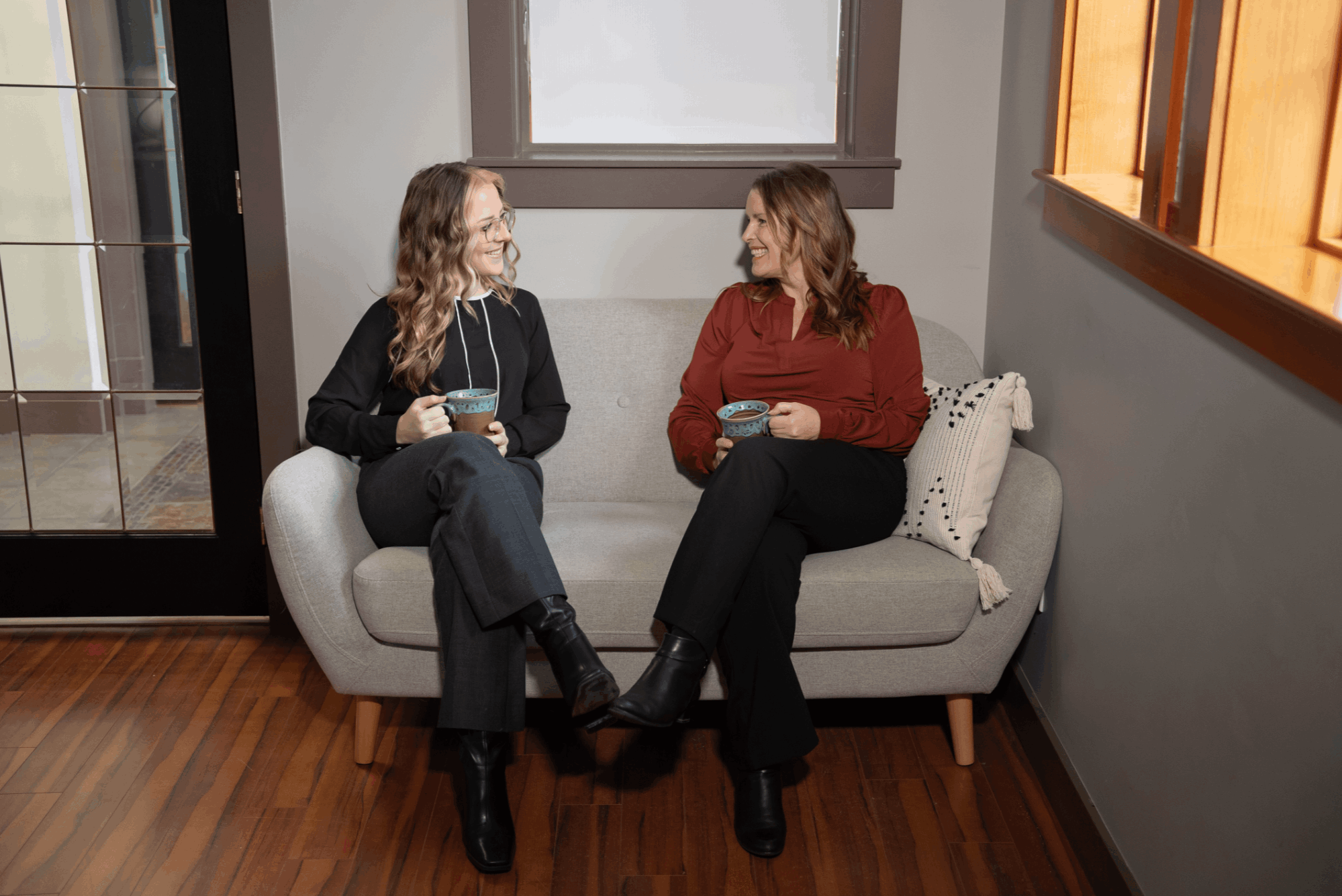 Two female realtors on vancouver island sitting on couch smiling