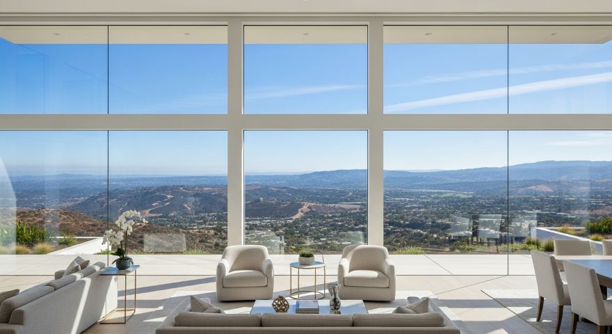 An illustrative image representing a modern home in San Diego's Del Cerro neighborhood with floor-to-ceiling windows and a panoramic canyon view, symbolizing the growing inventory and buyer opportunity in the real estate market.