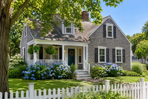 Gray cedar-shingle Cape Cod style home with porch and hydrangeas in Massachusetts