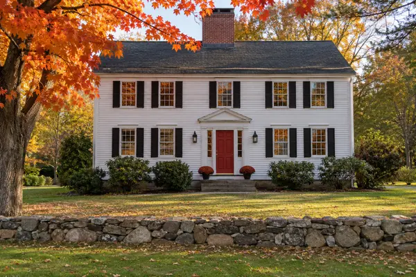 White center-chimney colonial home with stone wall in Suffield, Connecticut in autumn