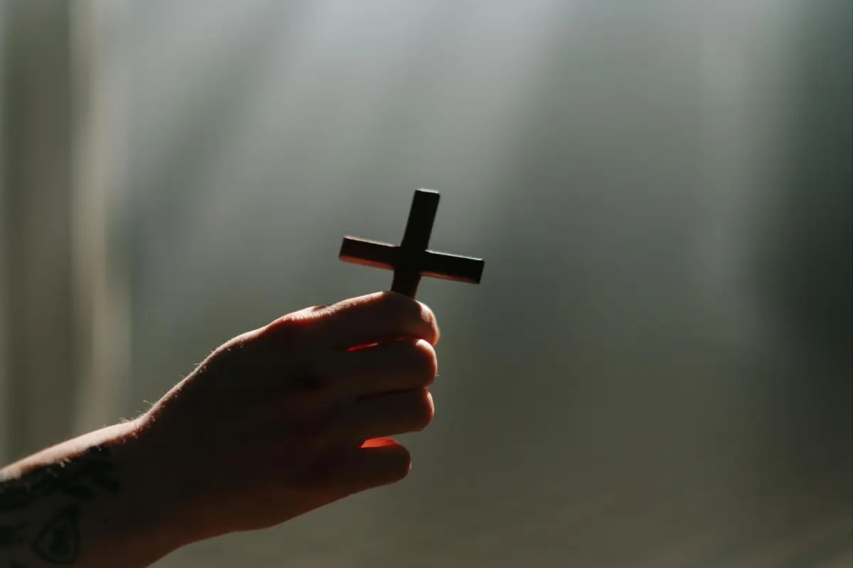 Faith-led approach to real estate, symbolized by person holding a cross