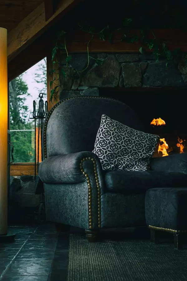 Big comfy chair in front of cozy fire place in a mountain cabin. 