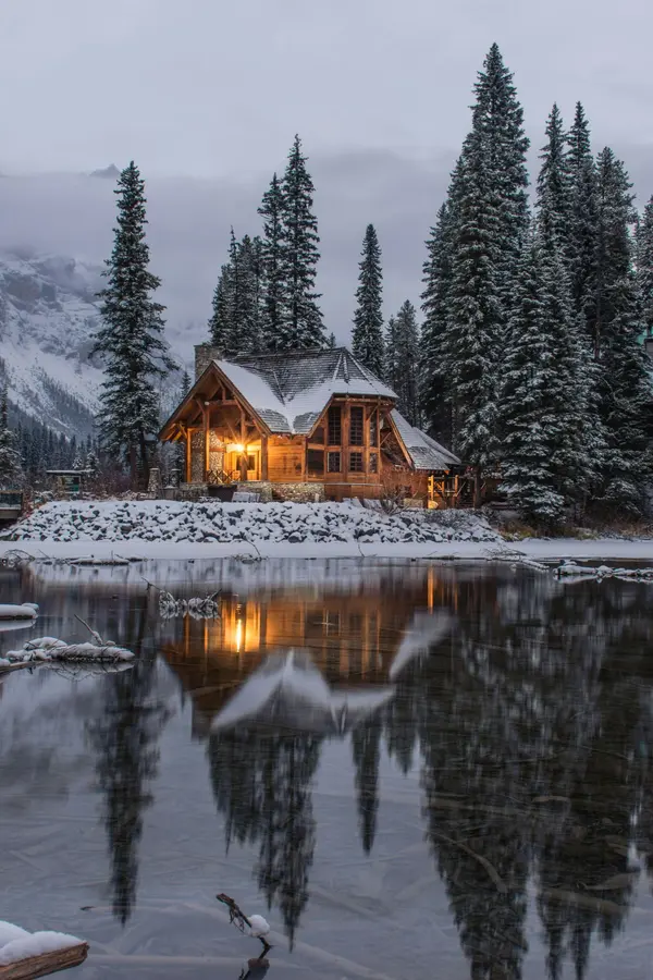 Mountain cabin on snow covered lake shore.