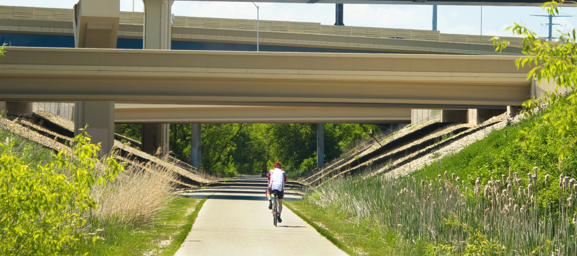 west allis, wisconsin bike rider passes under highway bridges above the Hank Aaron State Trail