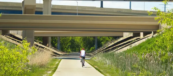 west allis, wisconsin bike rider passes under highway bridges above the Hank Aaron State Trail