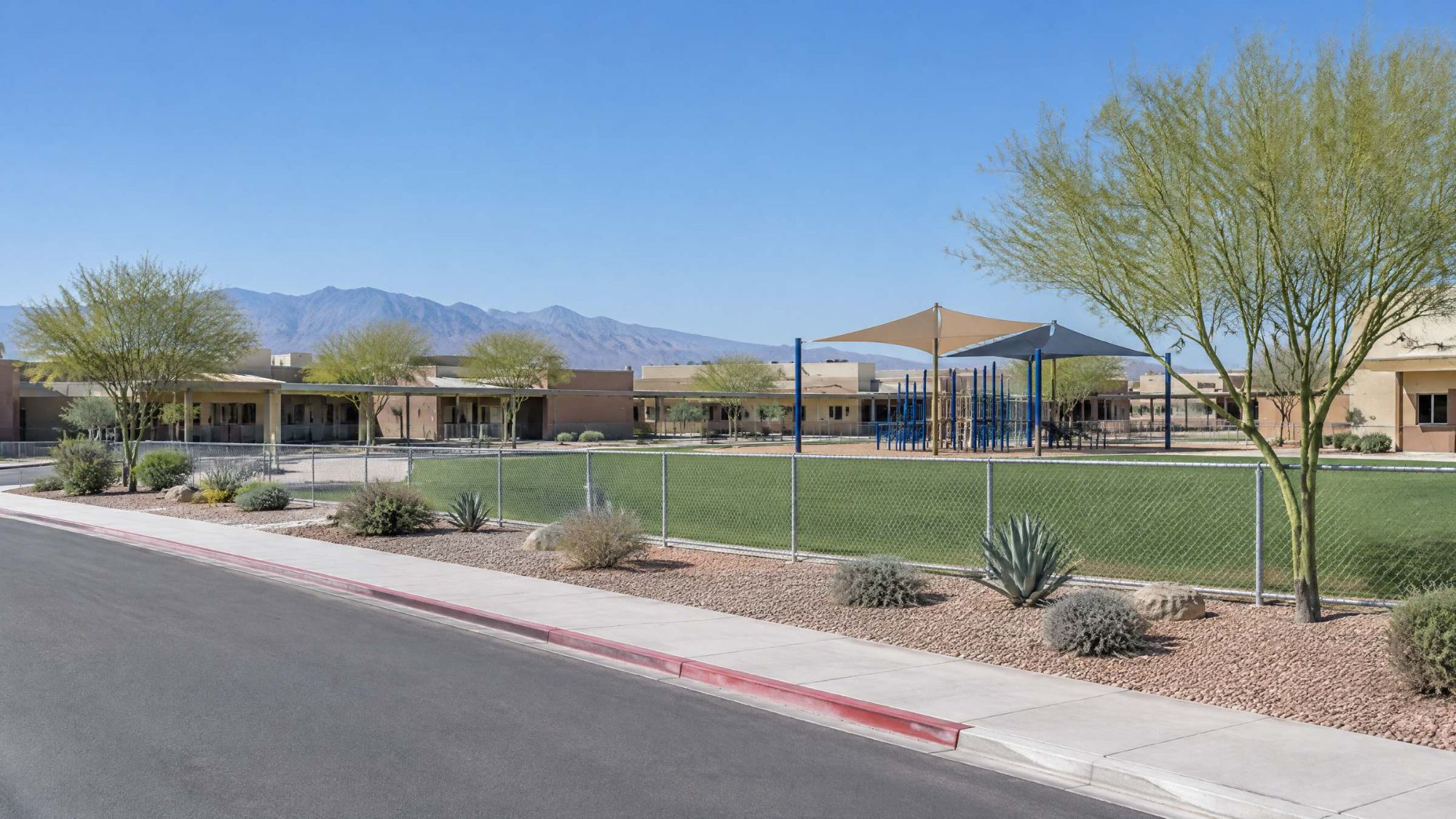 Illustration of a desert elementary school campus with a shaded playground and a grass field.