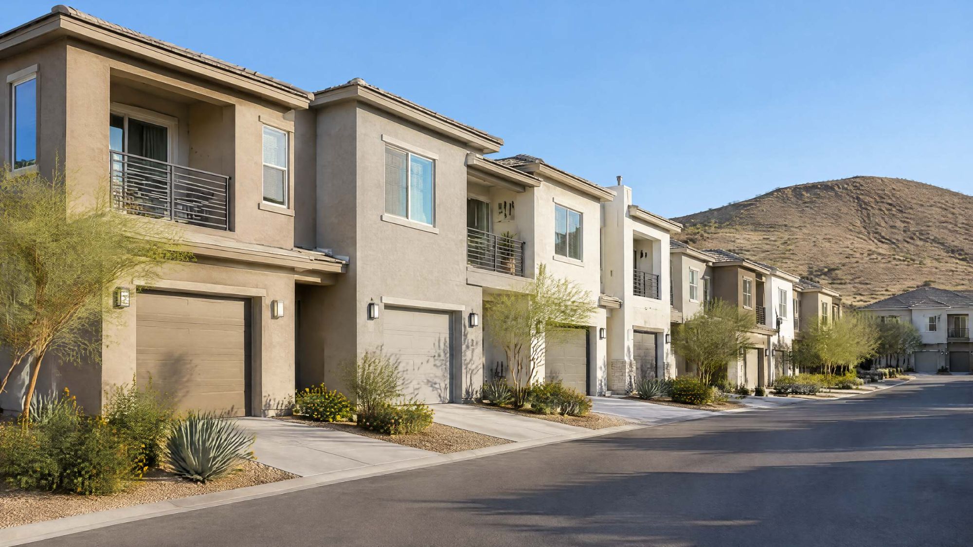 Illustration of a row of two-story townhomes with small balconies and desert landscaping.