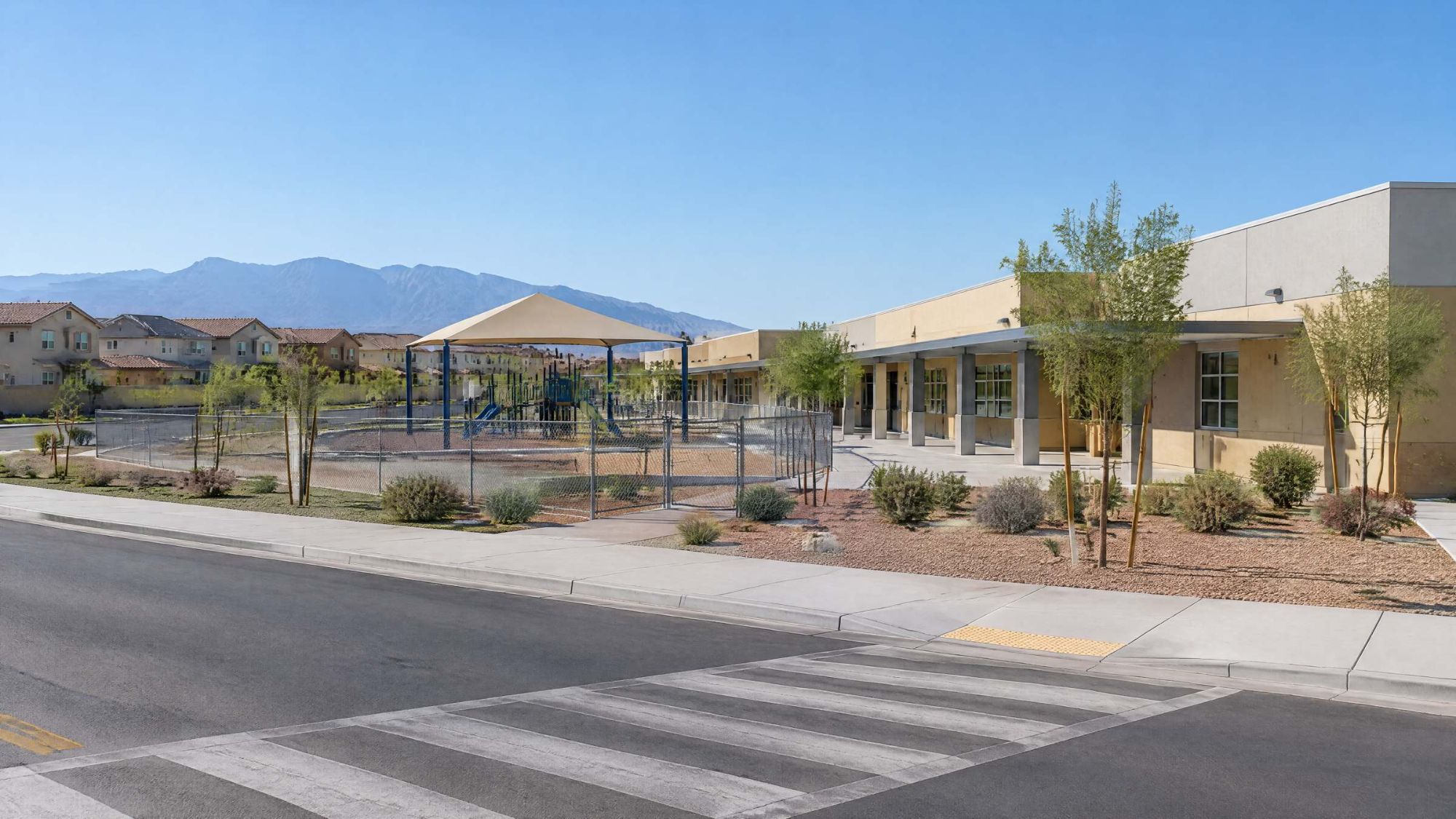 Illustration of a single-story public school with a shaded playground in a desert neighborhood.