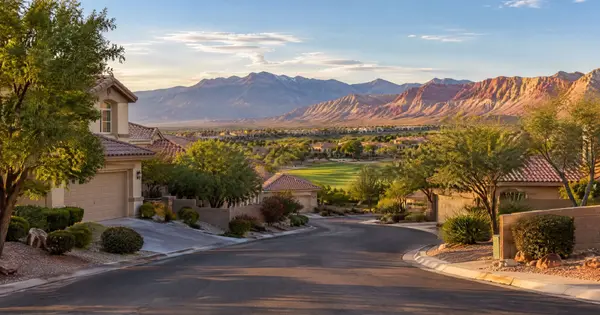 Mature tree-lined street with stucco, tile-roof homes and Red Rock mountains in The Hills, Summerlin