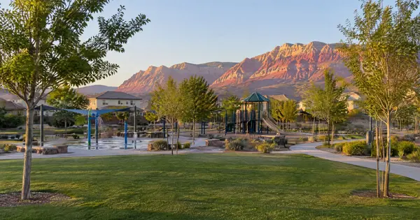 Neighborhood park ringed by stucco homes with Red Rock Canyon cliffs at sunset in Ridgebrook, Summerlin