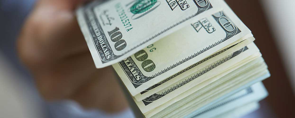 Hand holding hundred dollar bills