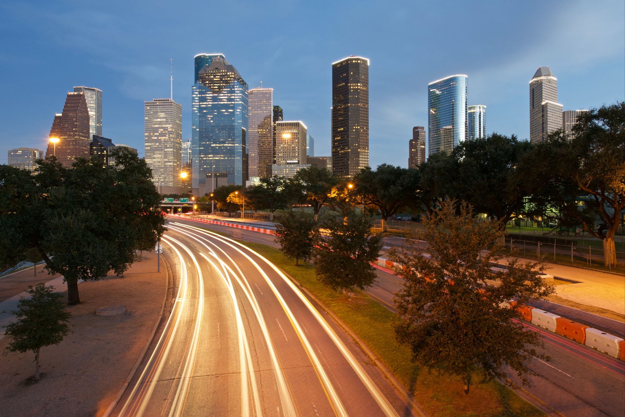 the Houston skyline at dusk, showcasing a time-lapse effect of traffic lights along a highway. 